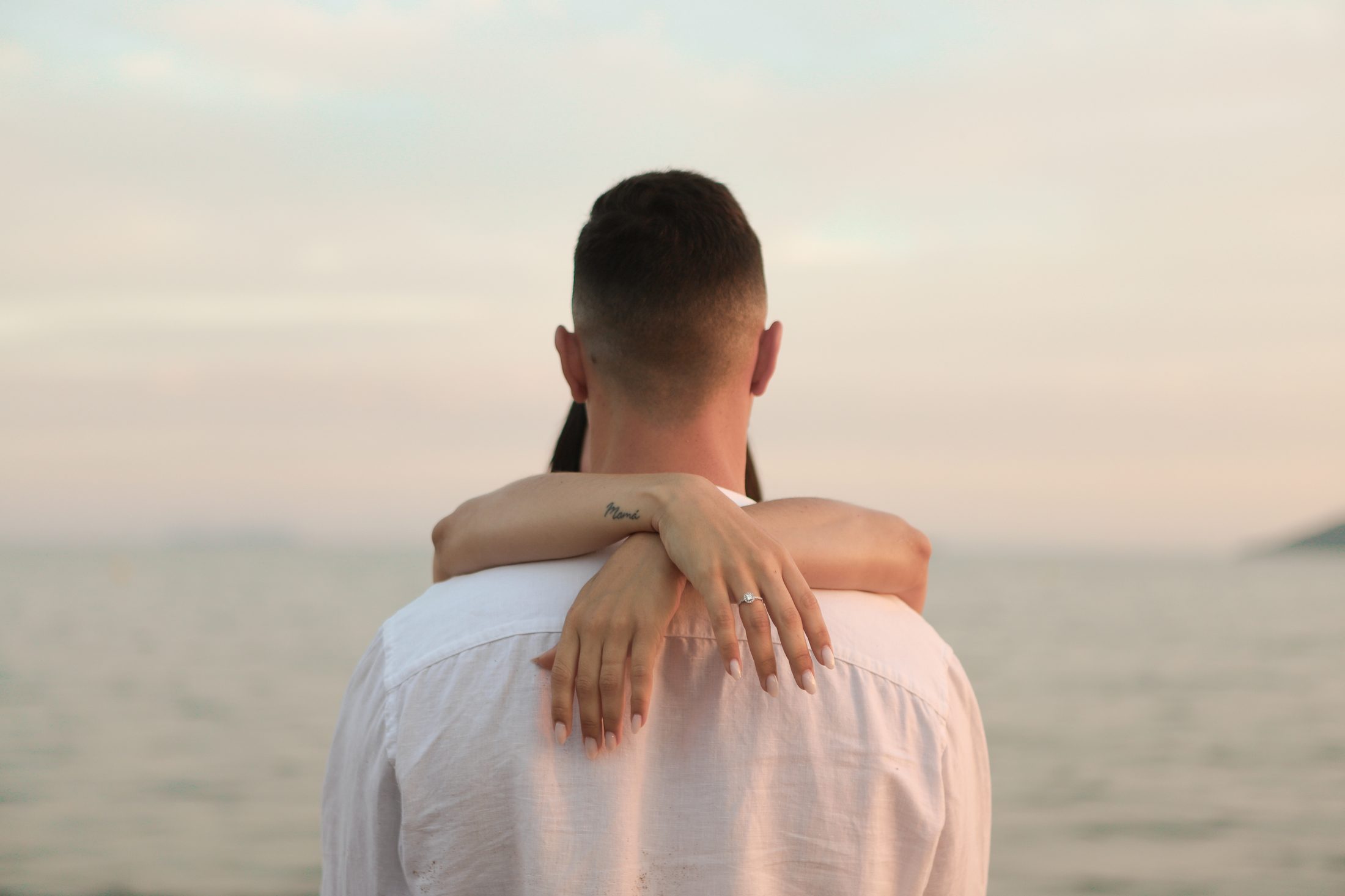 Pareja abrazada frente al mar al atardecer